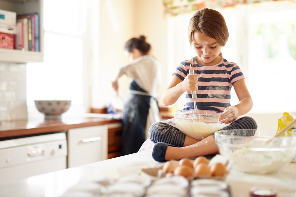 Young girl helping her mother bake
